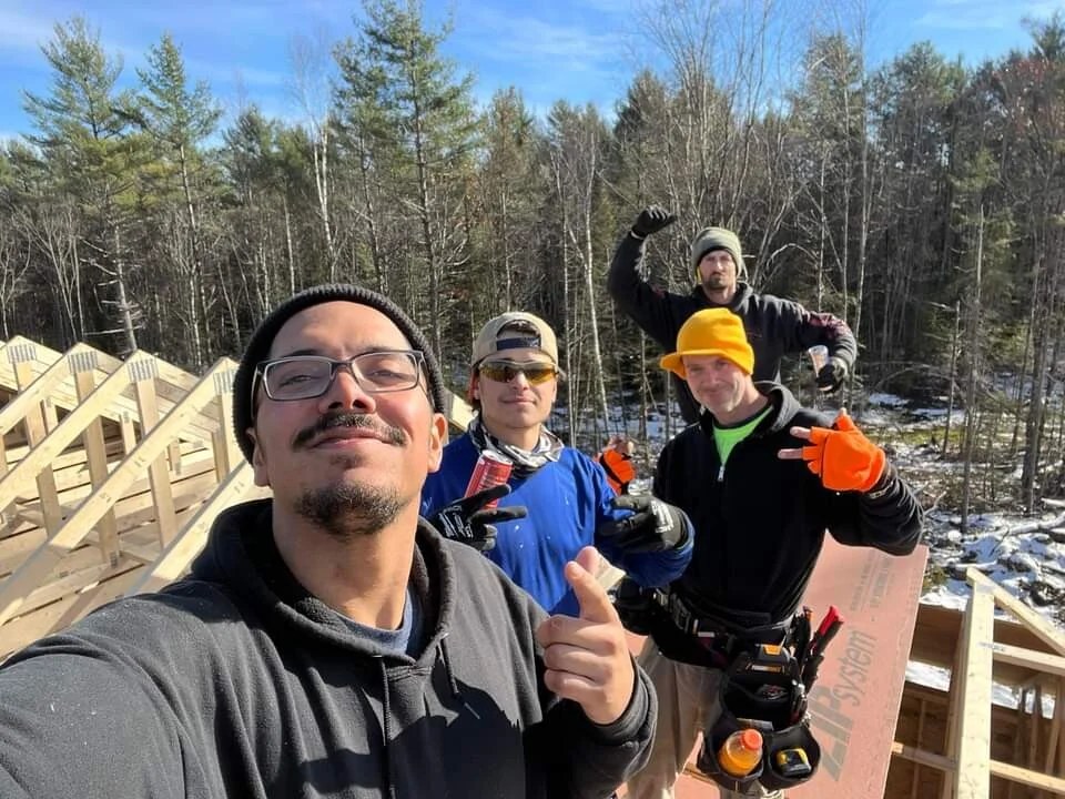 Superior Renovations LLC crew standing on the framing of a new home build in the snowy New Hampshire woods