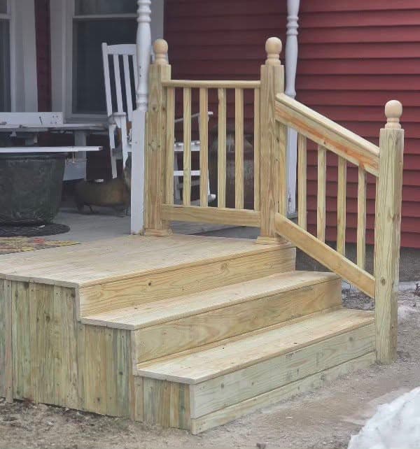 New pressure-treated deck landing and stairs with railings on a red house