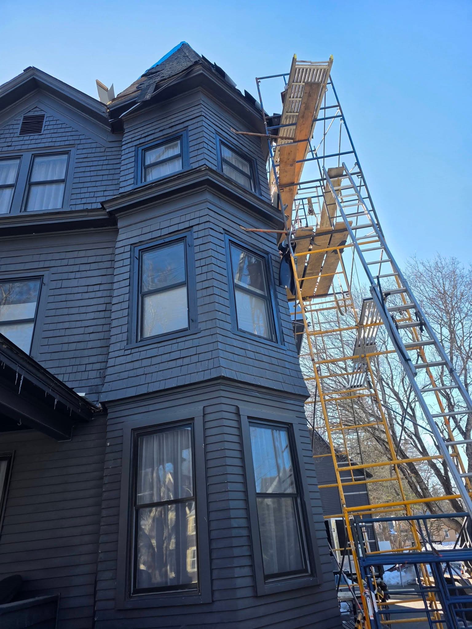 Bay window and turret detail of a Victorian home during roof work