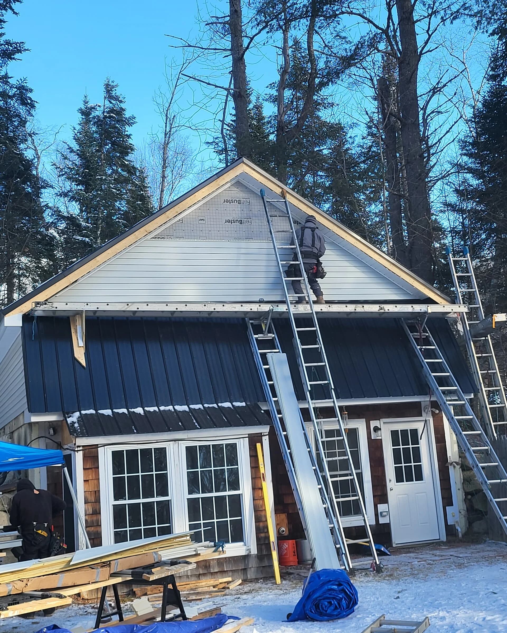 Superior Renovations crew installing new siding and metal roofing on a New Hampshire home